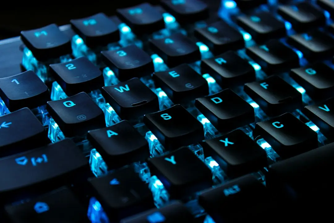 Close-up of a black keyboard with white backlit keys in the dark